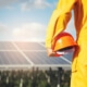Solar employee holding their helmet, facing a solar panel.