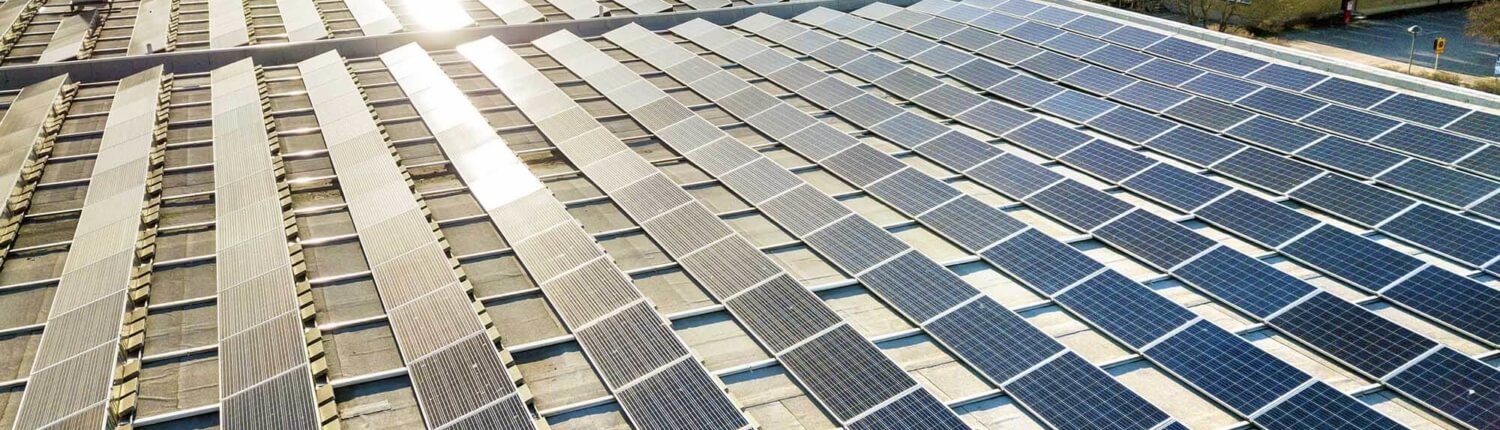 O3_commercial solar panels in rows on top of buildings Commercial solar panels with sun shining on them