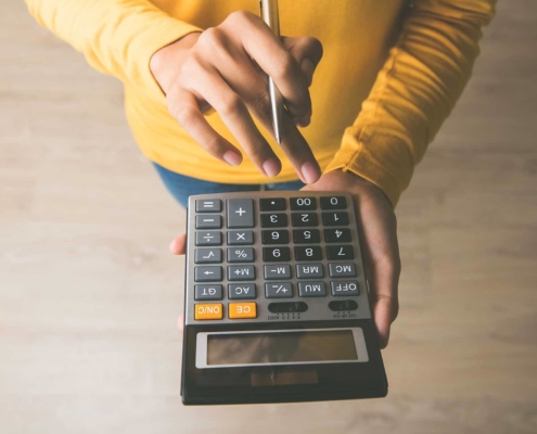 Person holding a pen and a calculator