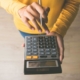 Person holding a pen and a calculator